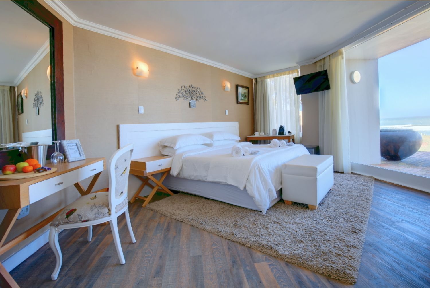 Une chambre d’hôtel avec un lit, un bureau, une chaise, une télévision et une vue sur l’océan.