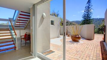 A modern interior with a glass door leading to a patio area, a wooden staircase, and a view of the outdoors.