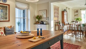 A spacious kitchen with a wooden island, a dining area with a table and chairs, and a view of the living room. - La Cotte House (Franschhoek)