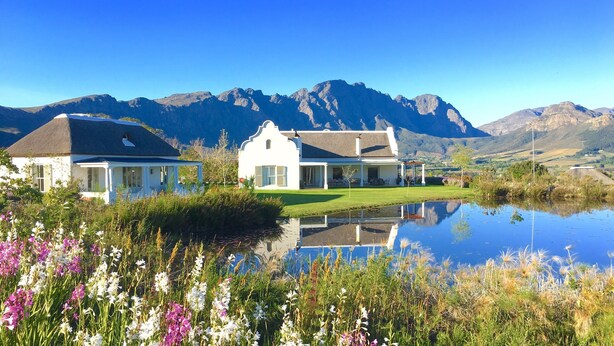 A house with a pond in front, surrounded by mountains. - La Cotte House (Franschhoek)
