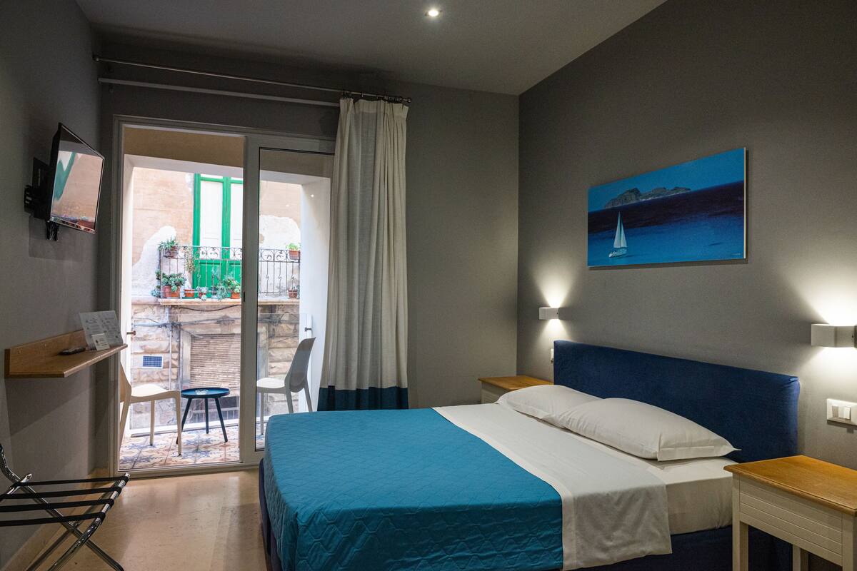 Ein Hotelzimmer mit Bett, Schreibtisch, Stuhl und Blick auf den Balkon.