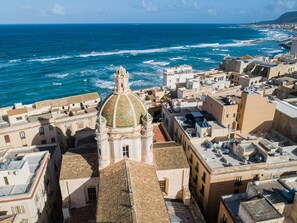 Un paisaje urbano costero con un edificio histórico destacado que tiene una cúpula y vistas al mar.