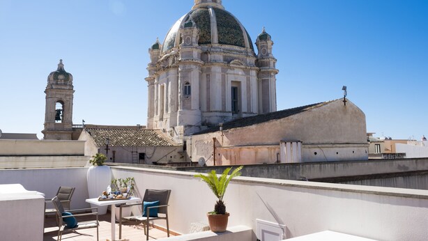 Une terrasse sur le toit offrant une vue sur un bâtiment historique doté d’un dôme et d’un clocher.