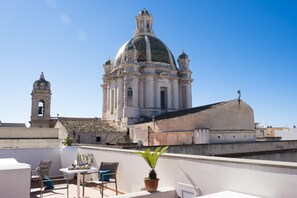 Une terrasse sur le toit offrant une vue sur un bâtiment historique doté d’un dôme et d’un clocher.