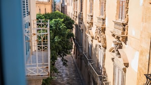 Une ruelle étroite pavée, bordée de bâtiments historiques aux détails architecturaux raffinés, et un chemin bordé d’arbres.