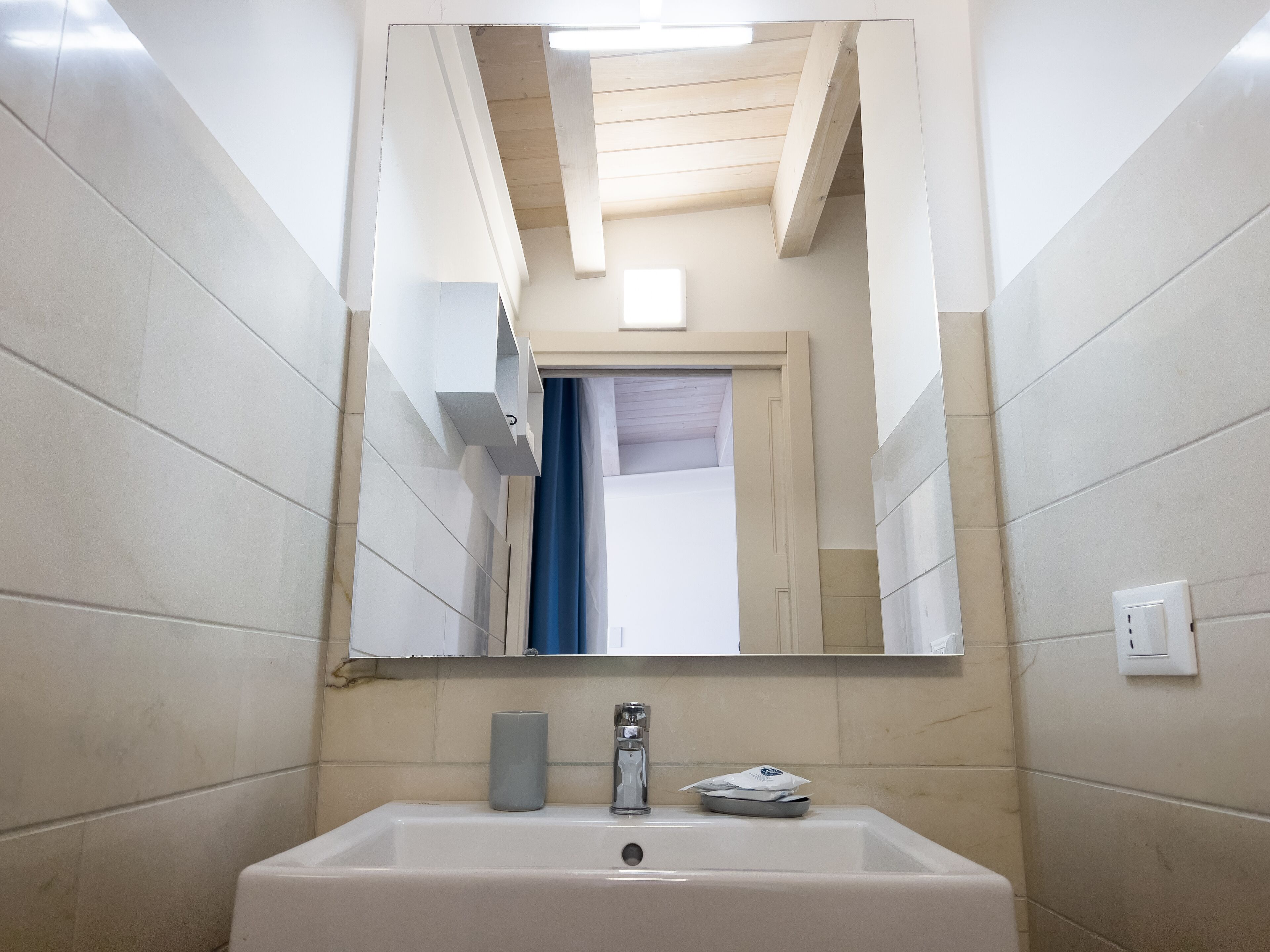 Un baño con un lavabo blanco, un espejo y un perchero para toallas.