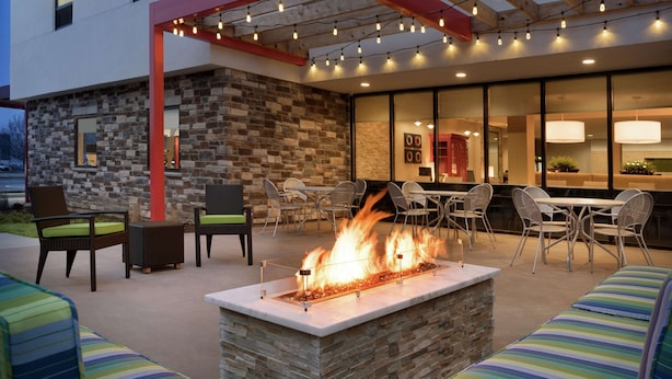 An outdoor patio with a stone fireplace, seating areas, and string lights. - Home2 Suites by Hilton Leavenworth Downtown (Leavenworth)