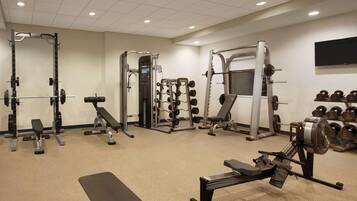 A gym with various exercise equipment including weight machines, a bench, and free weights.