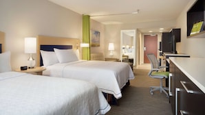 A hotel room with two beds, a desk, a chair, a TV, and a bathroom visible through an open door. - Home2 Suites by Hilton Leavenworth Downtown (Leavenworth)