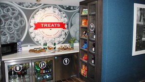 A bar area with a 'Treats' sign, a refrigerator stocked with beverages, and shelves with snacks.
