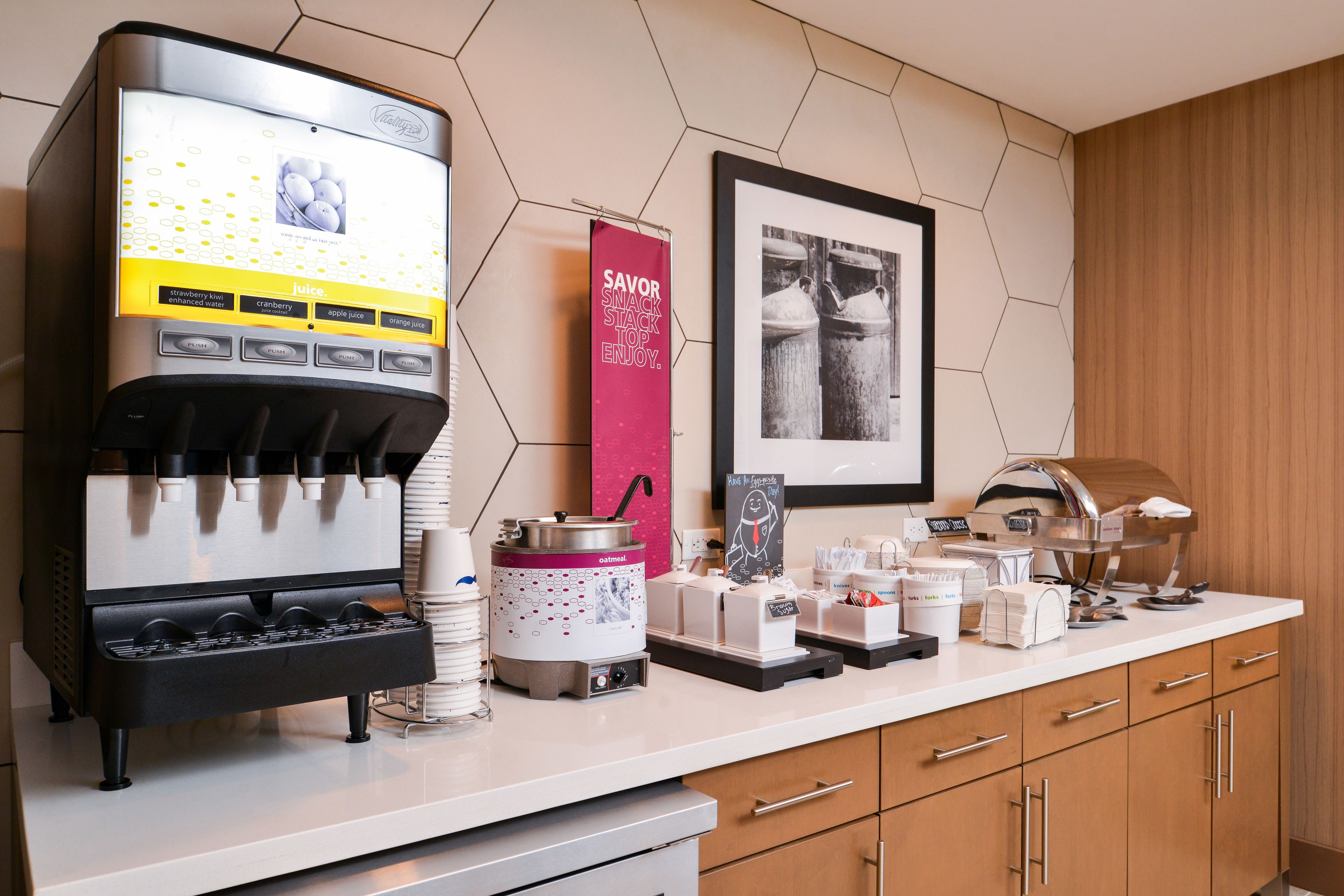 Eine Selbstbedienungs-Kaffeestation mit verschiedenen Getränkeoptionen, eine markenbezogene Kaffeemaschine und eine Theke mit diversen Zubehörteilen für die Kaffeezubereitung.