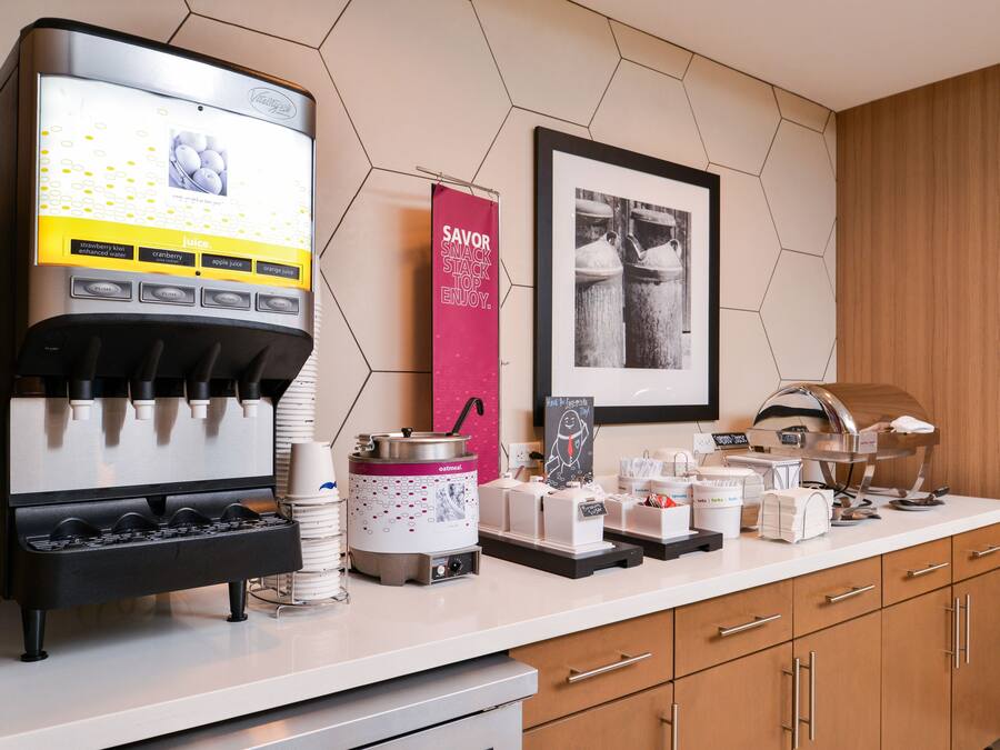 A self-serve coffee station with multiple beverage options, a branded coffee machine, and a counter with various coffee-making accessories.