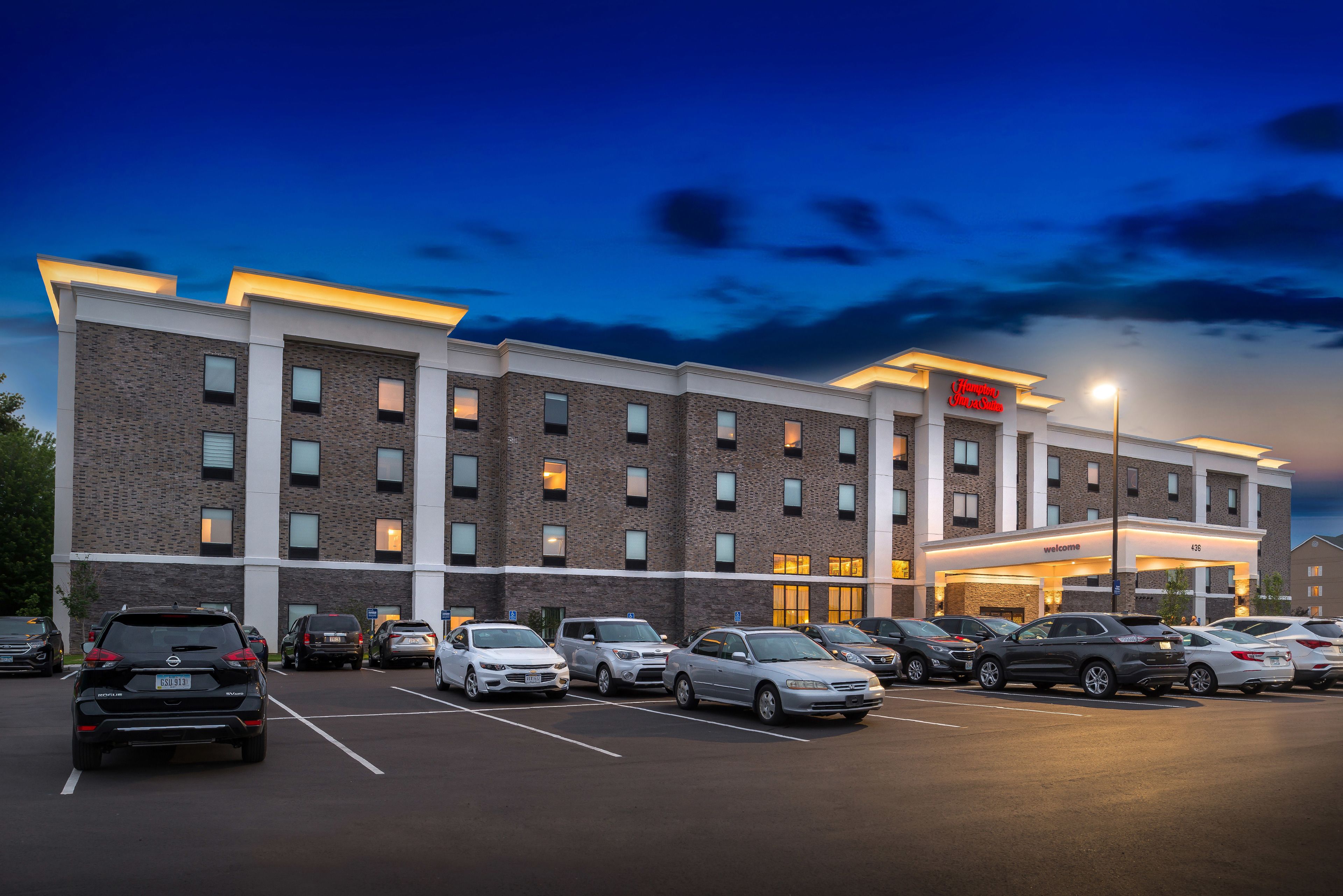 Un hôtel à plusieurs étages avec un parking rempli de voitures.
