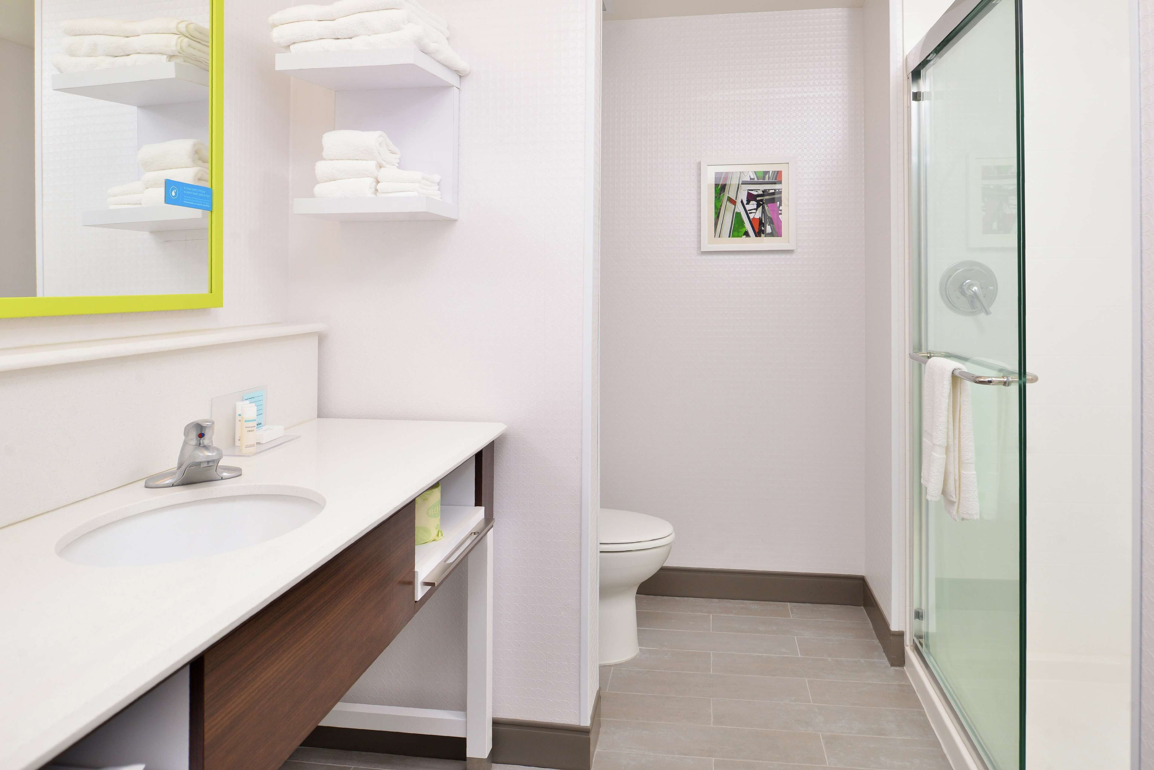 A modern bathroom with a white sink, mirror, and glass shower enclosure.