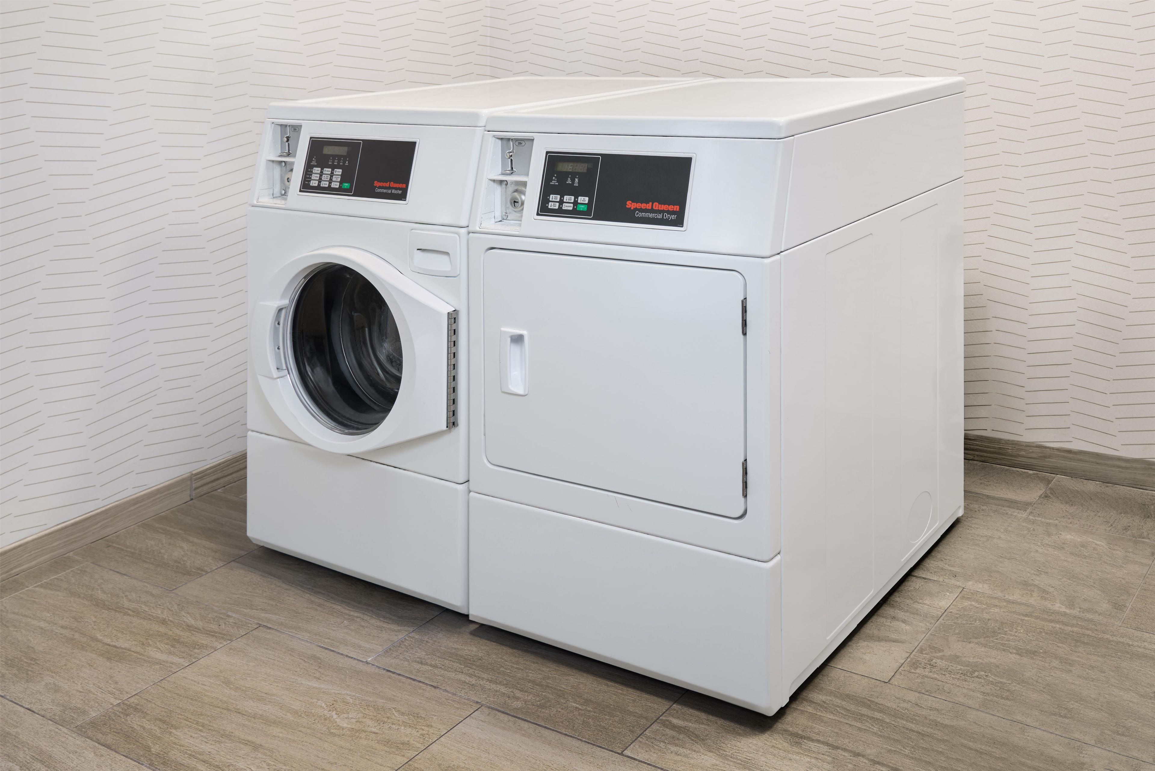 Un appareil combiné lave-linge et sèche-linge à chargement frontal, de couleur blanche, avec les commandes situées sur le dessus.