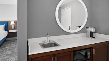 A hotel bathroom with a sink, mirror, and a coffee machine.