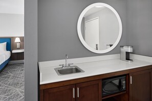 Une salle de bain d’hôtel équipée d’un lavabo, d’un miroir et d’une machine à café.