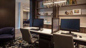 A hotel workspace with two desks, each with a computer and keyboard, surrounded by chairs. - Homewood Suites by Hilton Needham Boston (Needham)