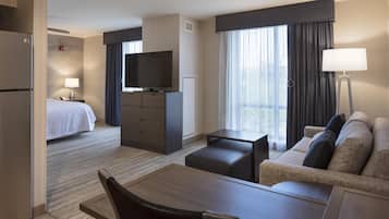 Een hotelkamer met een bed, een televisie, een bureau, een bank en een eethoek.