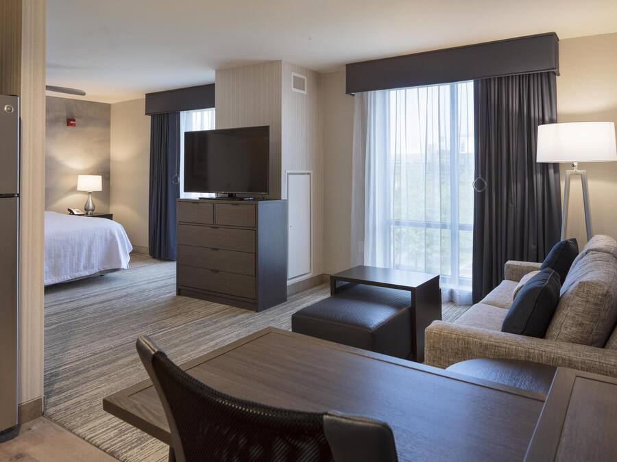 Een hotelkamer met een bed, een televisie, een bureau, een bank en een eethoek.