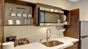 Een moderne keuken met een roestvrijstalen spoelbak, een magnetron en een koelkast.