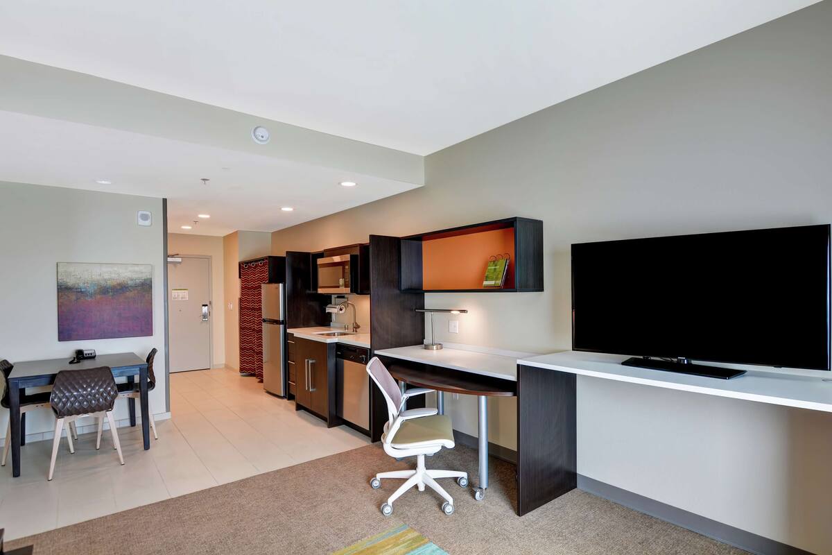 Un apartamento moderno con comedor, kitchenette y un televisor grande.