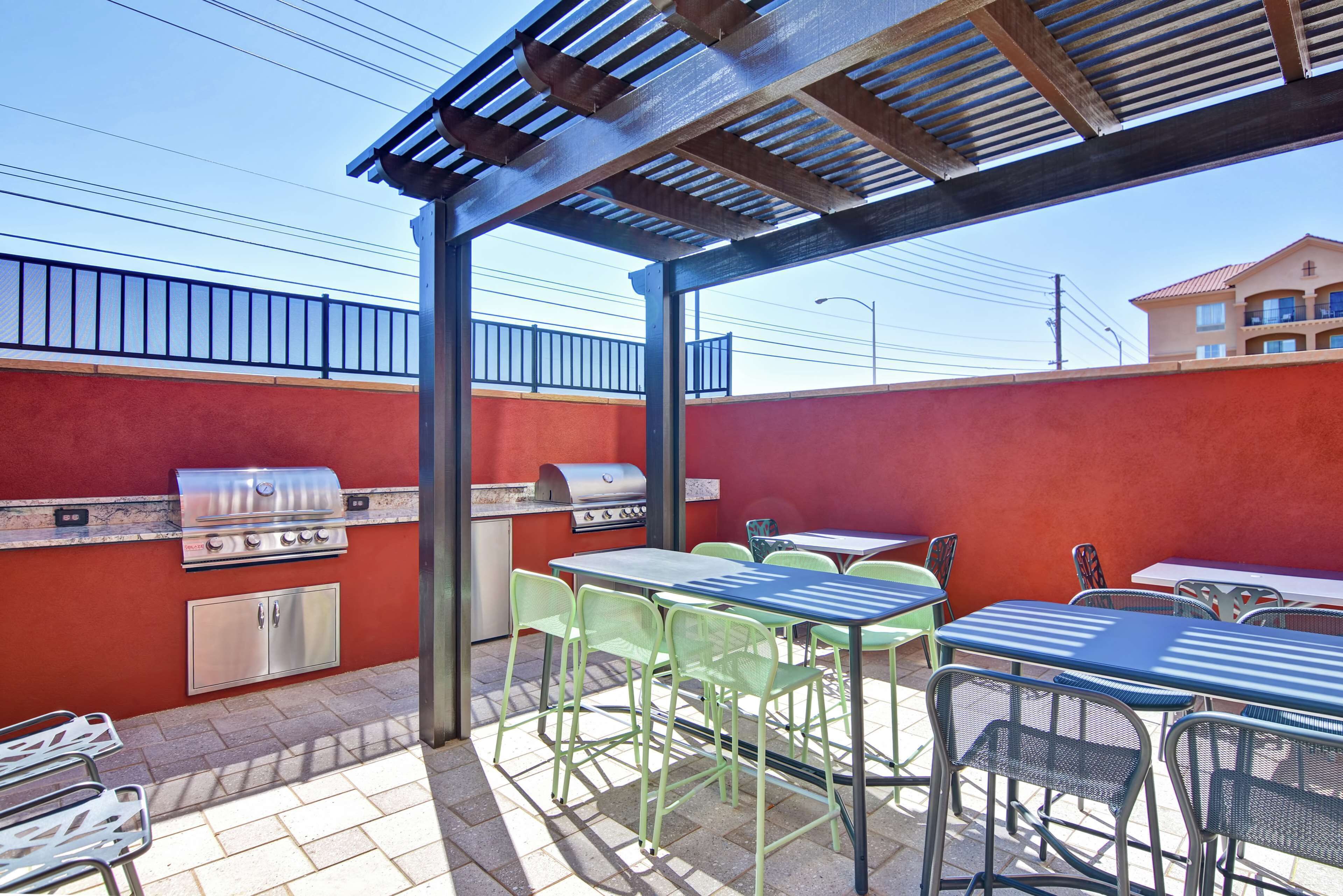 An outdoor patio with a grill, tables, and chairs.