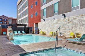 An outdoor swimming pool with lounge chairs and a stone wall. - Home2 Suites by Hilton Las Vegas Strip South (Las Vegas)