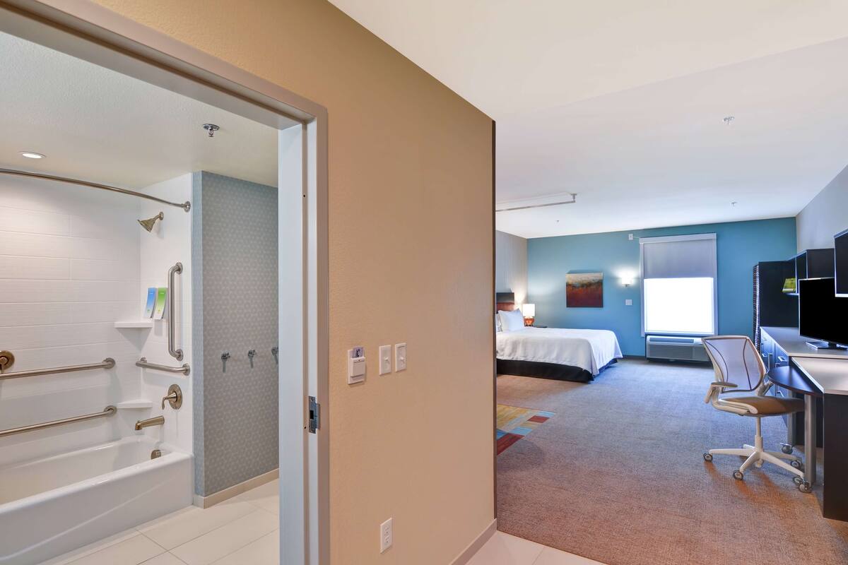 Habitación de hotel con bañera, cama, escritorio y televisión.
