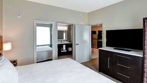 Ein Hotelzimmer mit Bett, Fernseher, Badezimmer mit Spiegel und Kleiderschrank.