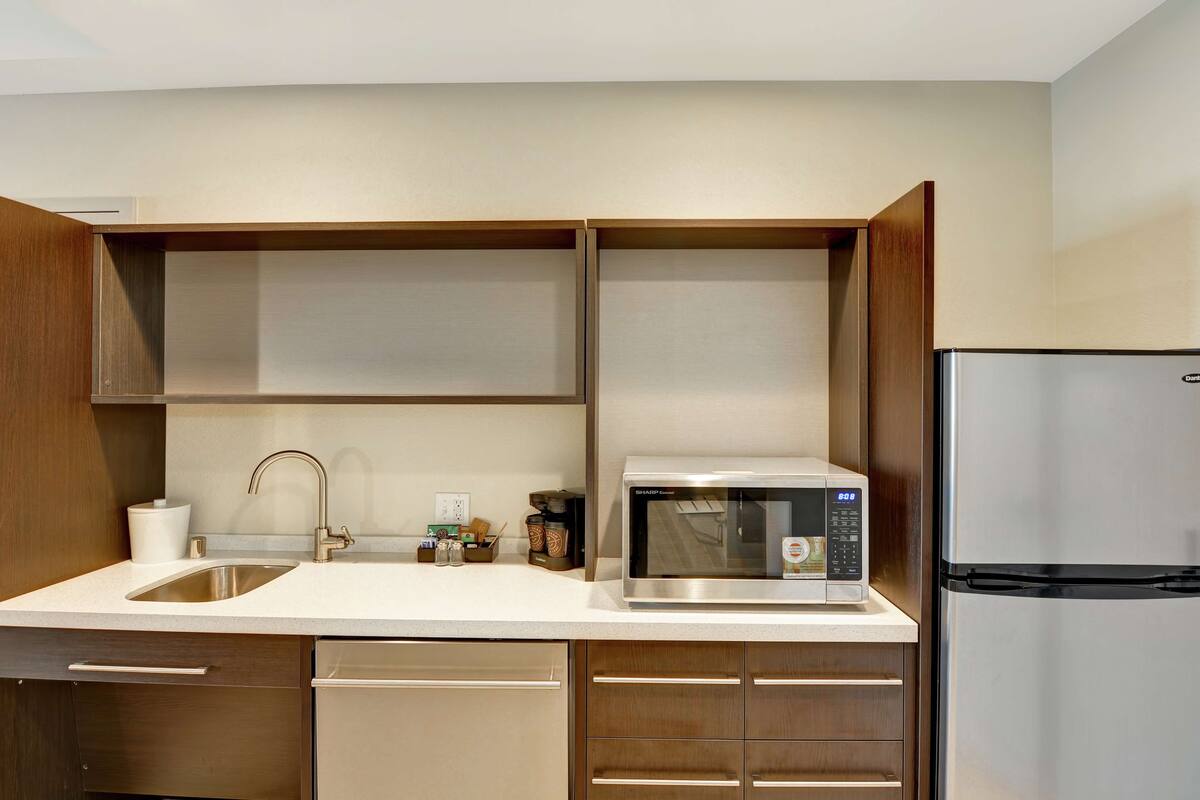 Una cocina moderna con un refrigerador de acero inoxidable, un microondas y un lavamanos.