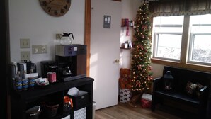 A living room with a wooden clock, a coffee machine, a Christmas tree, and a sofa. - Briarwood Motor Inn (Lincoln)