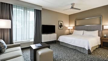 Una habitación de hotel con cama, televisión, escritorio, silla y ventilador de techo.
