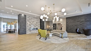 Un'ampia zona giorno con un lampadario moderno, una parete decorata in pietra e un'area pranzo con tavolo e sedie.