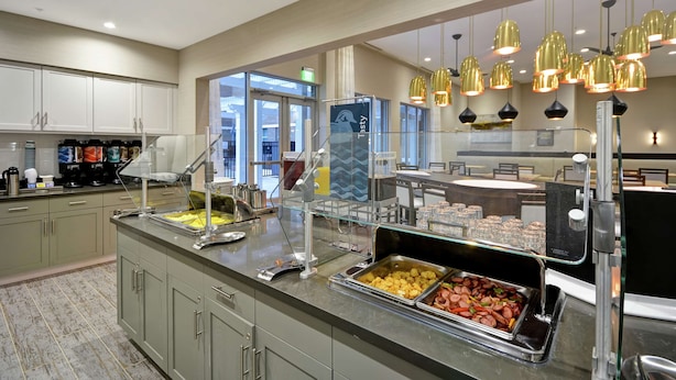 Un'area buffet con diverse opzioni gastronomiche, un angolo caffè e un pannello di vetro.