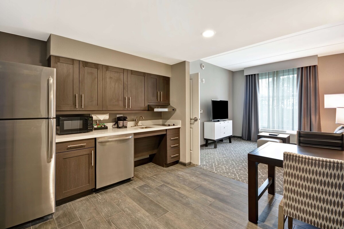 A modern kitchen with stainless steel appliances, wooden cabinets, and a dining area with a table and chairs.