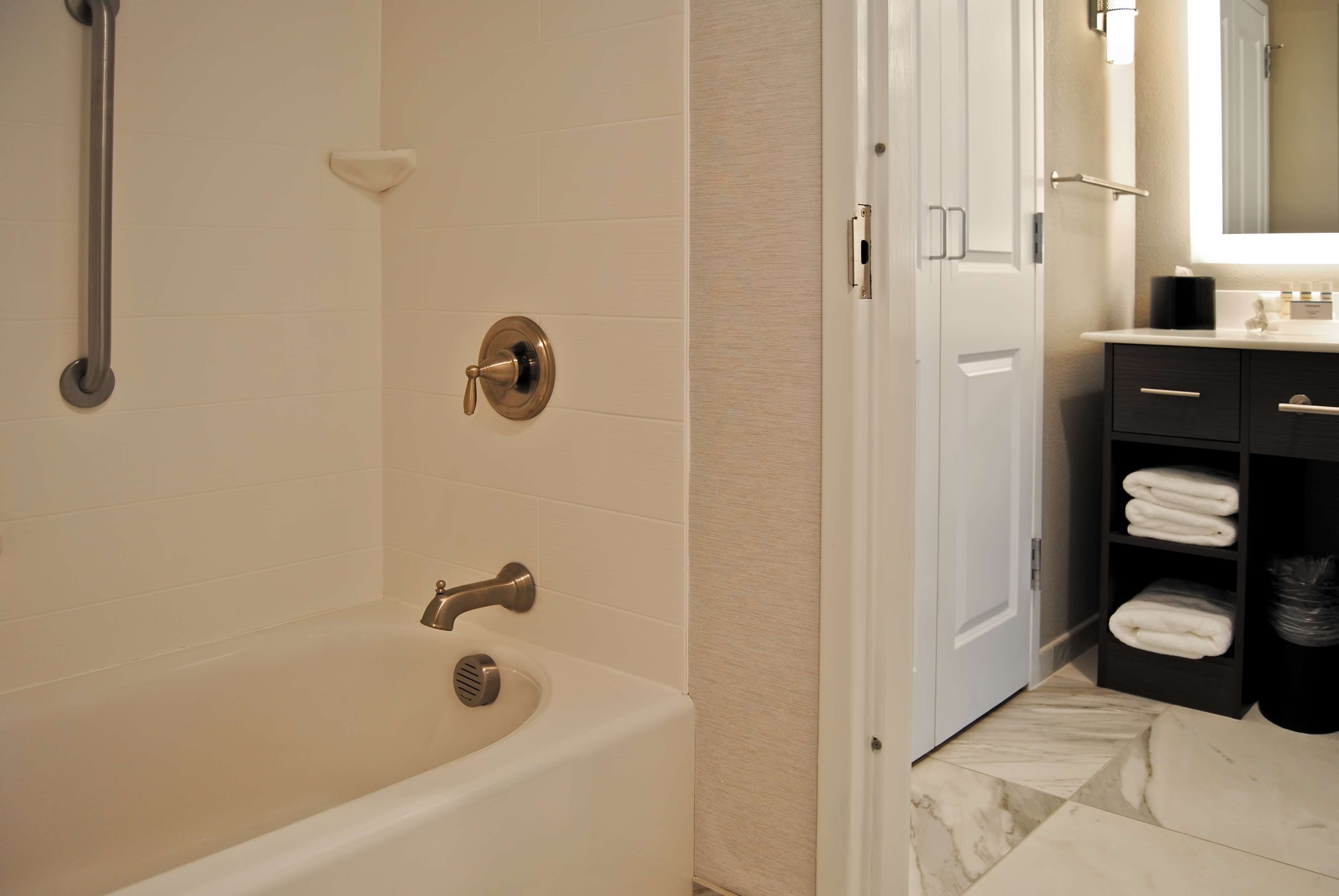 Une salle de bain moderne équipée d’une baignoire, d’une douche et d’un meuble-lavabo avec un miroir.