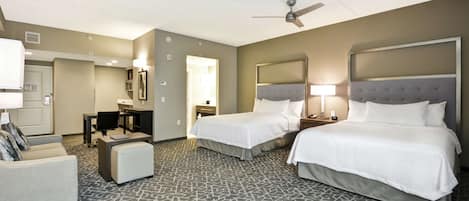 Une chambre d’hôtel avec deux lits, un bureau, une chaise et un canapé.