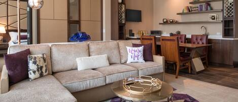A modern living room with a sectional sofa, a coffee table, and a dining area with a table and chairs.
