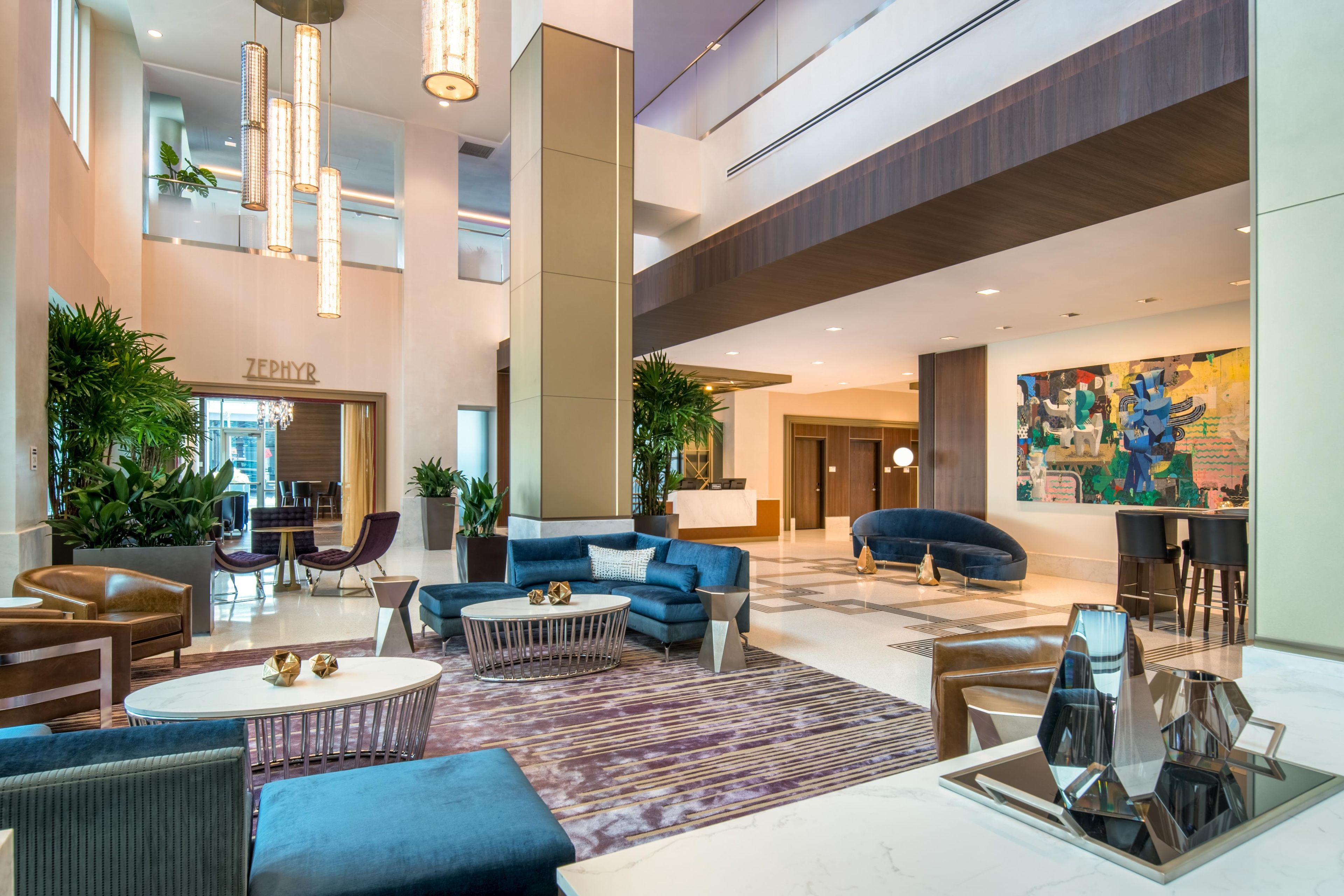 A spacious lobby with a seating area, a reception desk, and a large abstract painting on the wall.