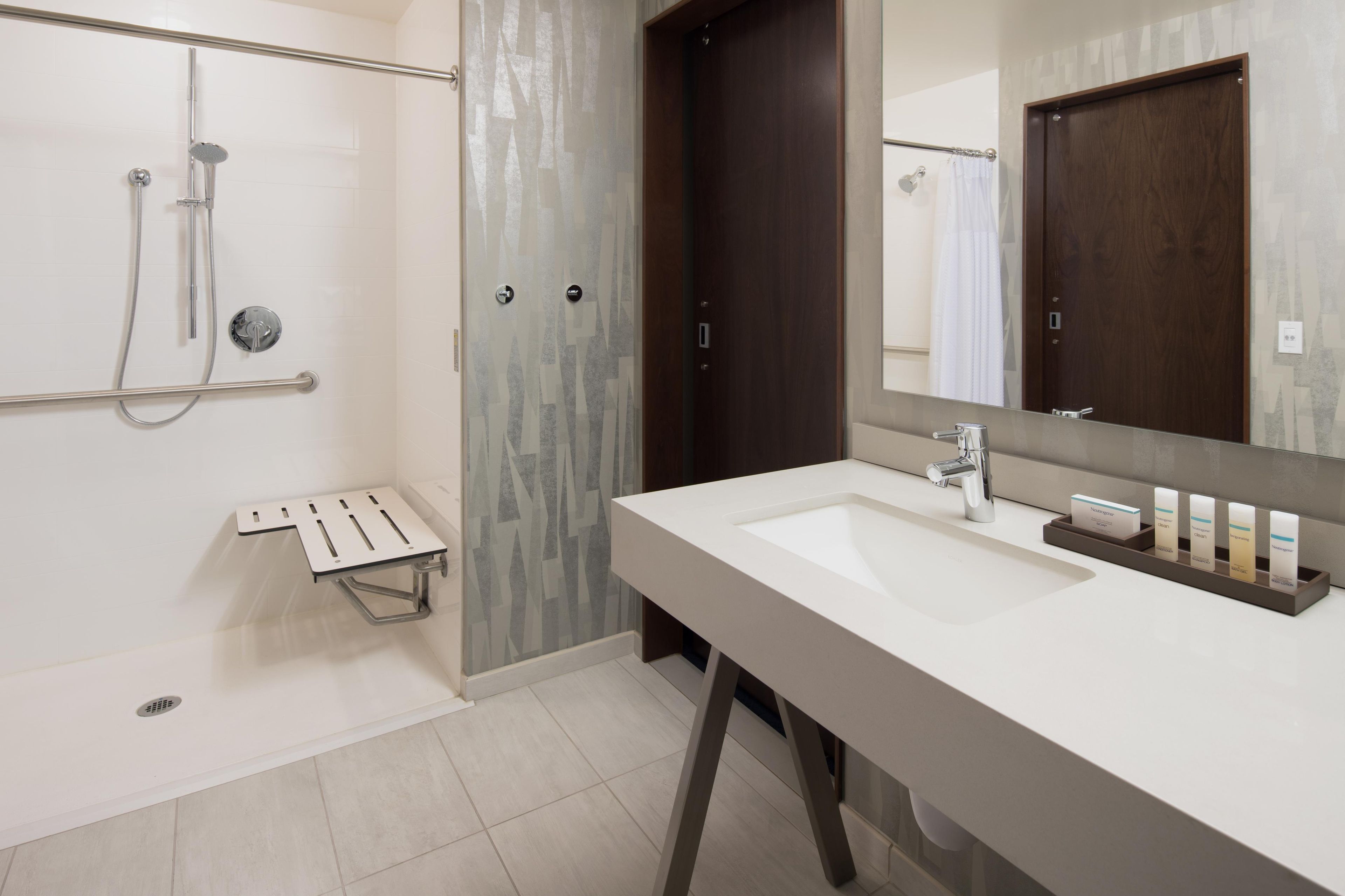 A modern bathroom with a shower, a sink, and a mirror.