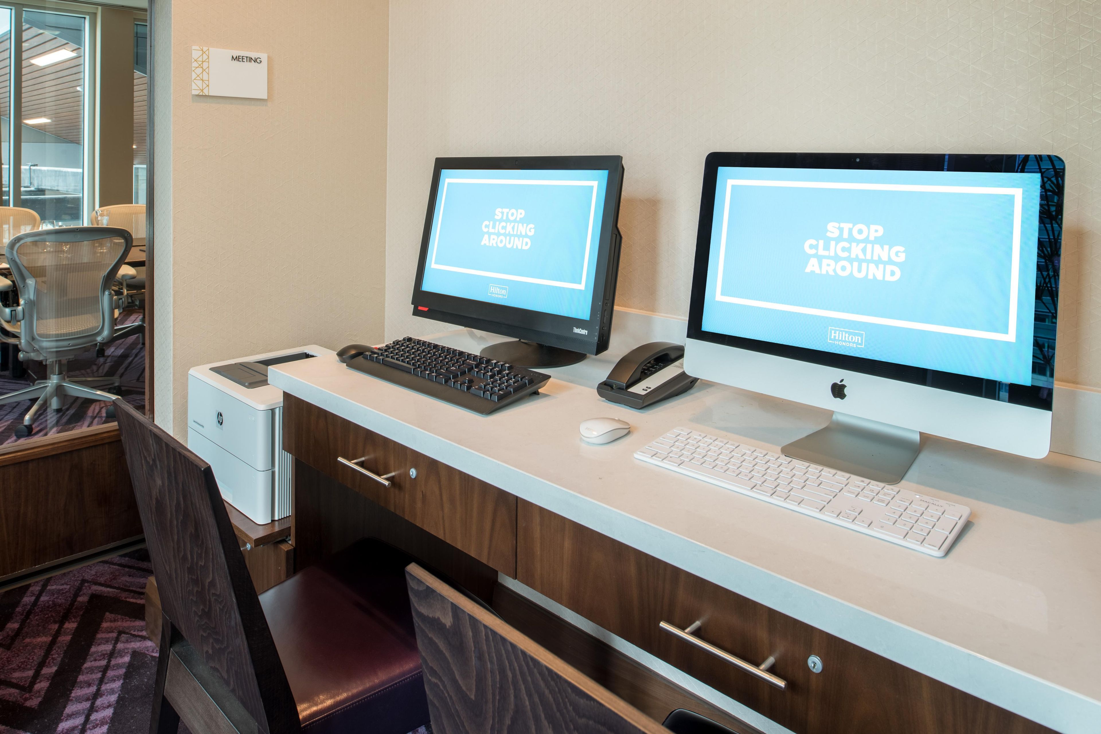 Taulell de recepció d'hotel amb dos monitors que mostren un missatge, un teclat, un ratolí, un telèfon i una impressora.