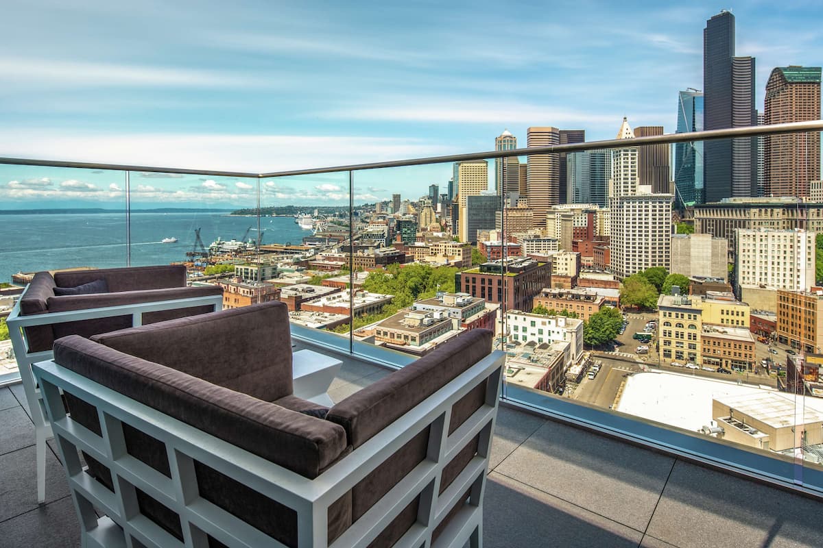 A high-rise balcony with a city view, including a waterfront and modern buildings.