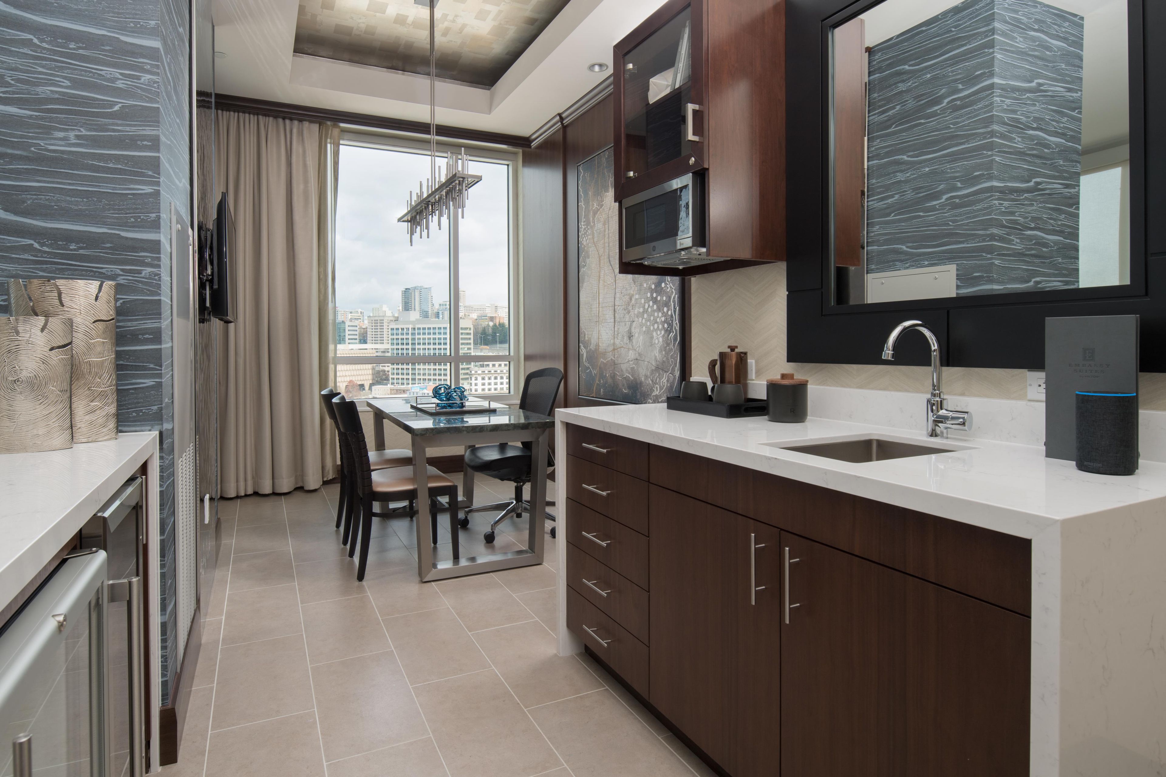 A modern kitchen with a built-in microwave, a sink, and a large window offering a city view.