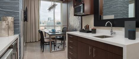 A modern kitchen with a built-in microwave, a sink, and a large window offering a city view.
