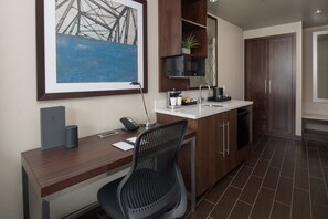 A modern kitchen with a wooden countertop, a microwave, a sink, and a chair. - Embassy Suites by Hilton Seattle Downtown Pioneer Square (Seattle)