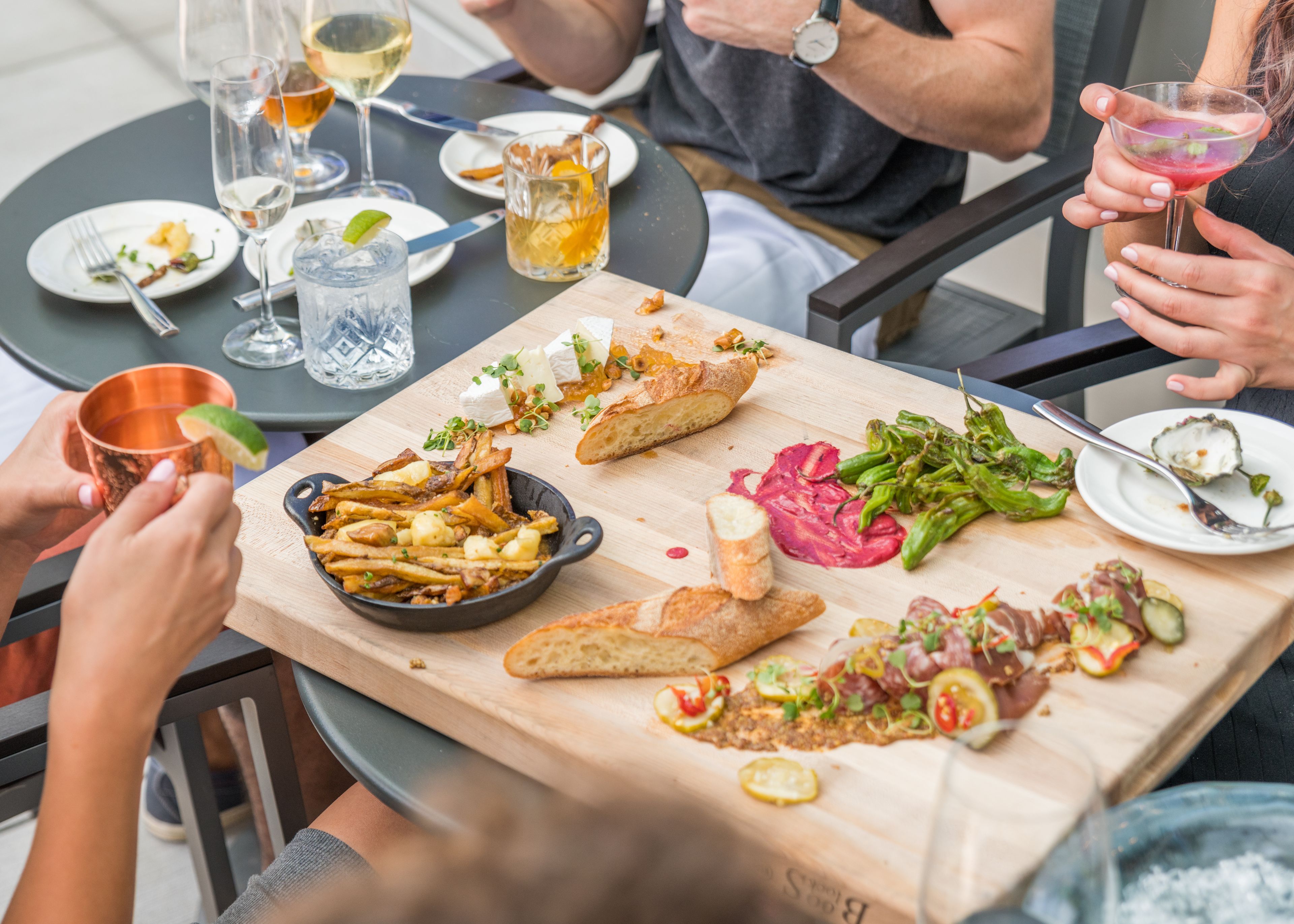 A dining table with various dishes, including fries, cheese, and vegetables, and several glasses of beverages.