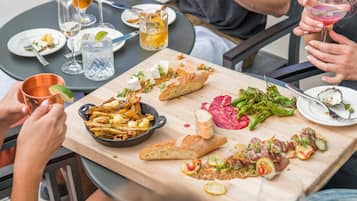A dining table with various dishes, including fries, cheese, and vegetables, and several glasses of beverages.
