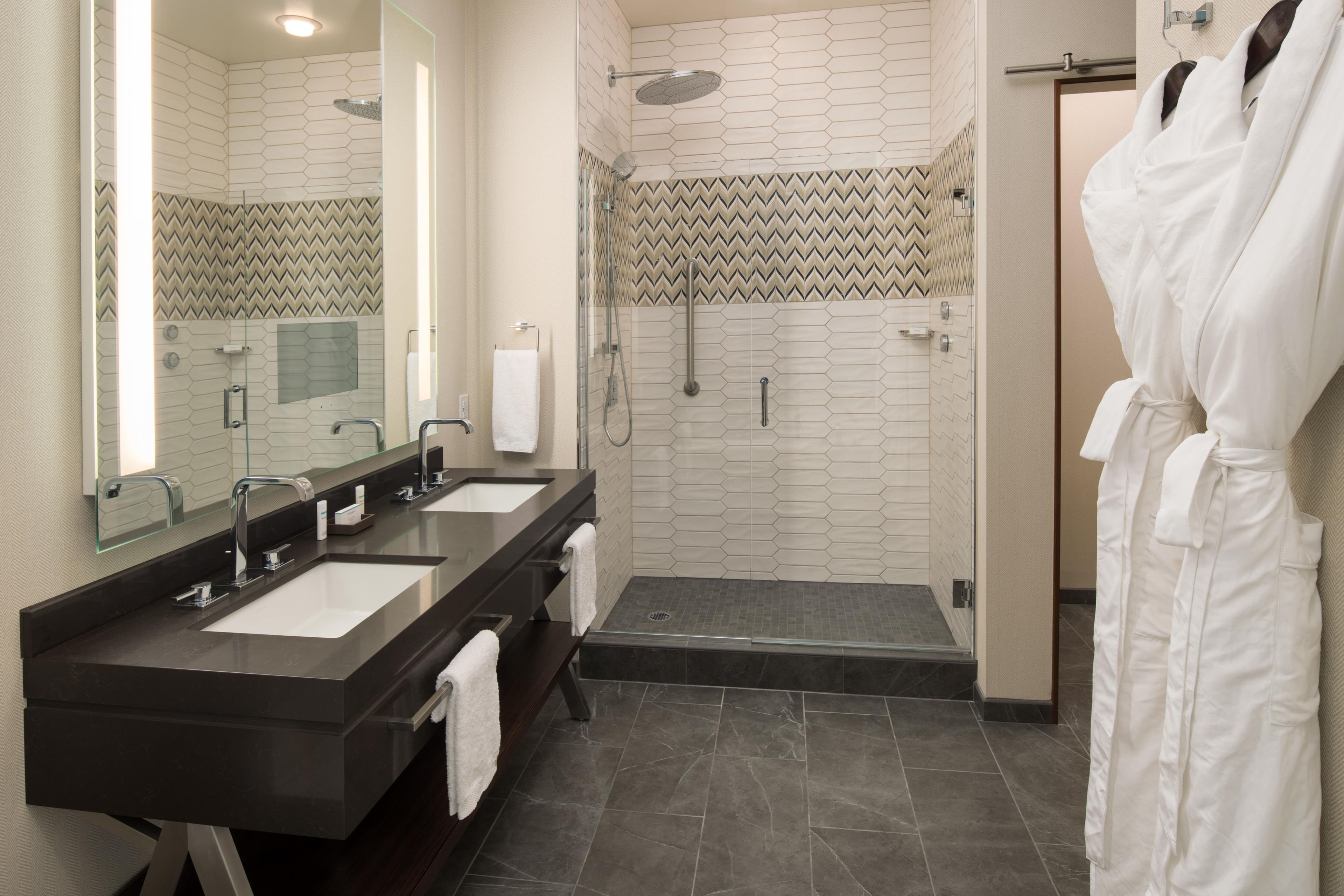 Un baño moderno con lavamanos dobles, cabina de ducha de vidrio y plato de ducha integrado.