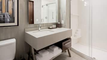 A modern bathroom with a white sink, a mirror, a shower, and a toilet.